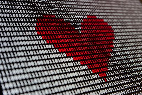 A screen full of ones and zeroes, some of which are colored red and form the shape of a heart.